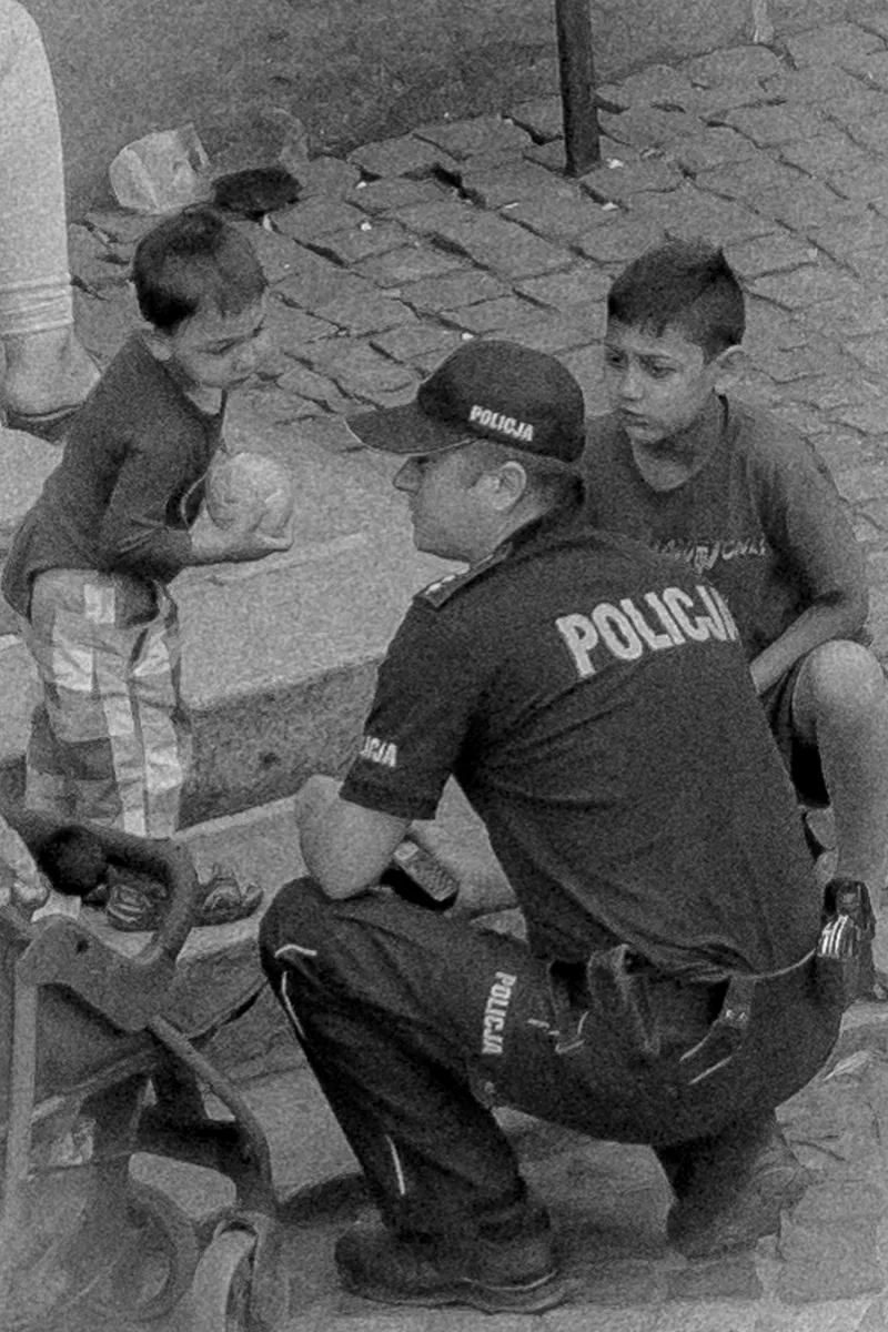 Police officer crouching beside two boys seated on church steps